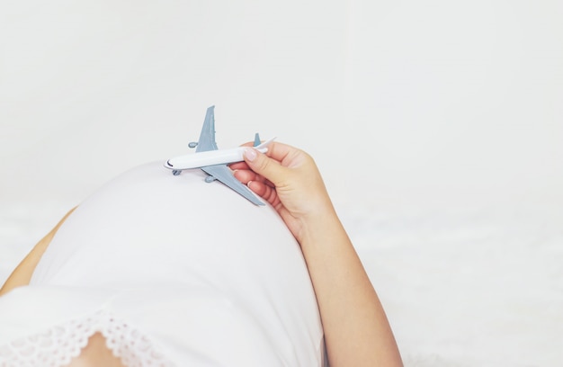 Uma mulher grávida está segurando um avião.