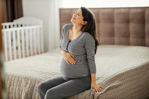 Uma mulher grávida está tendo dor de estômago enquanto está sentada em um quarto