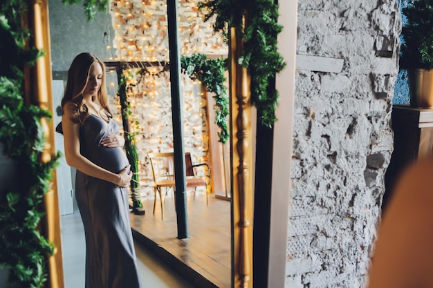 Uma mulher grávida feliz olha amorosamente para o reflexo dela mesma e de seu bebê por nascer no espelho