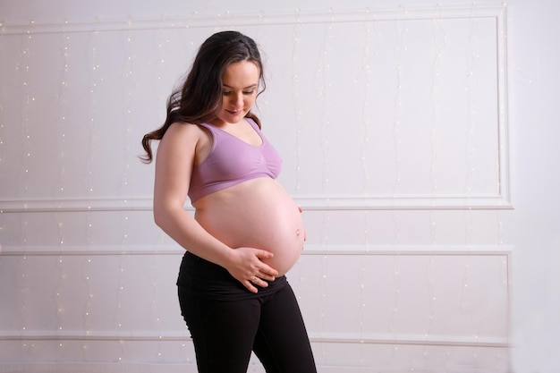 Uma mulher grávida se levanta e toca sua barriga nua