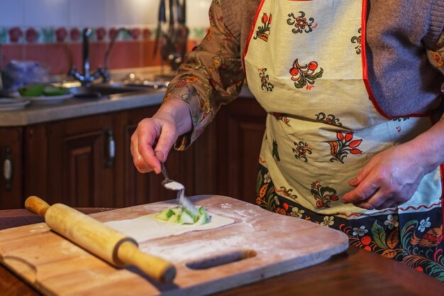 Uma mulher idosa de avental prepara tortas na cozinha