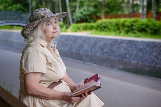 Uma mulher idosa lê um livro no parque