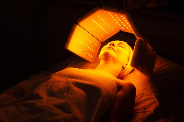 Uma mulher idosa passa por um procedimento de rejuvenescimento facial mulher enfrenta um tratamento de luz vermelha em beau