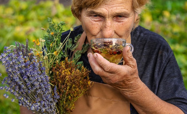 Uma mulher idosa prepara chá de ervas Foco seletivo