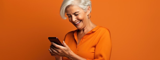 Foto uma mulher idosa sorrindo e rindo com seu telefone contra um fundo colorido