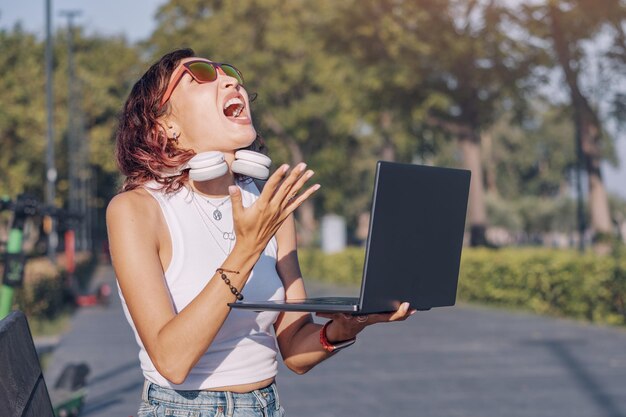 Uma mulher irritada e irritada xinga e levanta o punho para o laptop por causa de problemas na escola de trabalho ou uma conexão de Internet interrompida