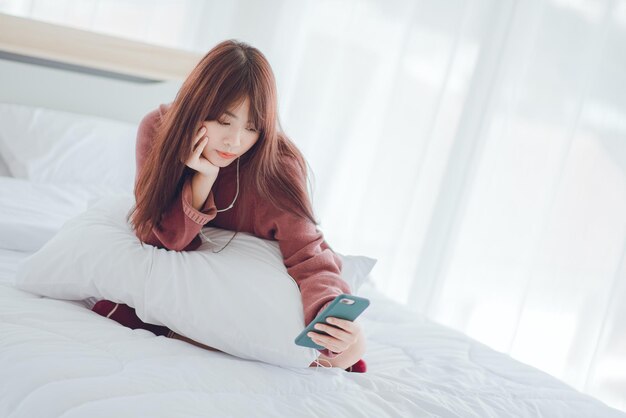 Uma mulher jogando no telefone na cama em casa