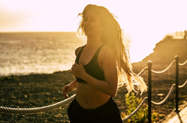 Uma mulher jovem e saudável corre ao ar livre para um estilo de vida de exercícios físicos rotina matinal de corrida para pessoas ativas pôr do sol e vista para o mar em segundo plano conceito de estilo de vida de cuidados com a saúde e o corpo