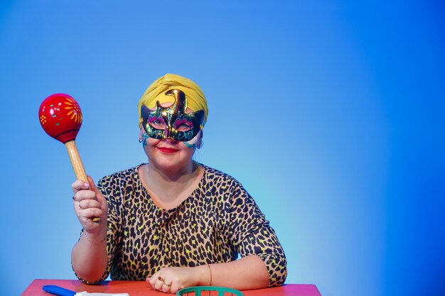 Foto uma mulher judia com um cocar e uma máscara de carnaval comanda quando fazer barulho na sinagoga