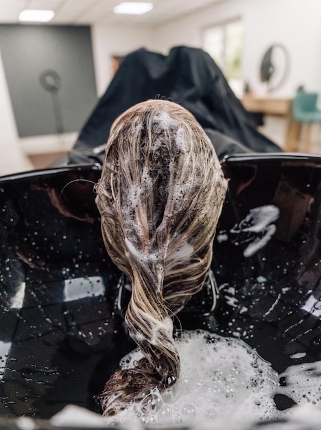 Uma mulher lava o cabelo com shampoo lavagem do cabelo do salão de beleza