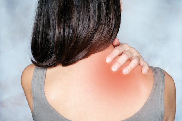 Uma mulher massageia seu ombro e pescoço pontos de dor pontos gatilho massagem fisioterapia e conceito de massagem