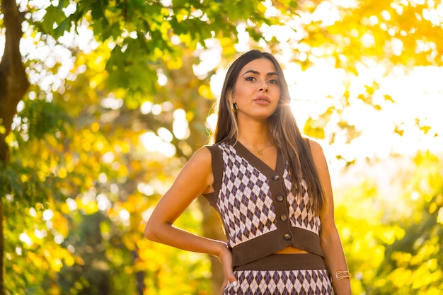 Uma mulher morena caucasiana no outono ao pôr do sol em um parque natural da cidade