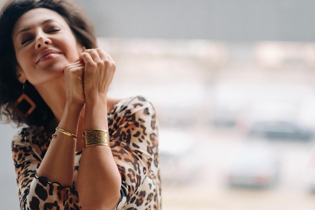 Foto uma mulher morena com um vestido de tigre está perto de uma grande janela.