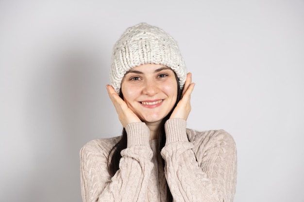 Uma mulher morena feliz com um chapéu de inverno e um suéter tricotado sorri