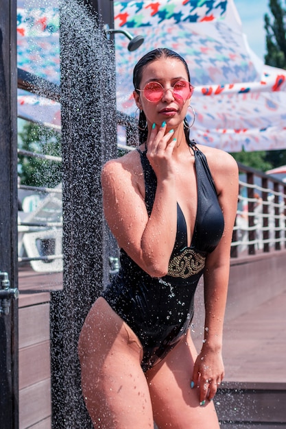 Uma mulher morena toma um banho ao ar livre, um banho perto da piscina