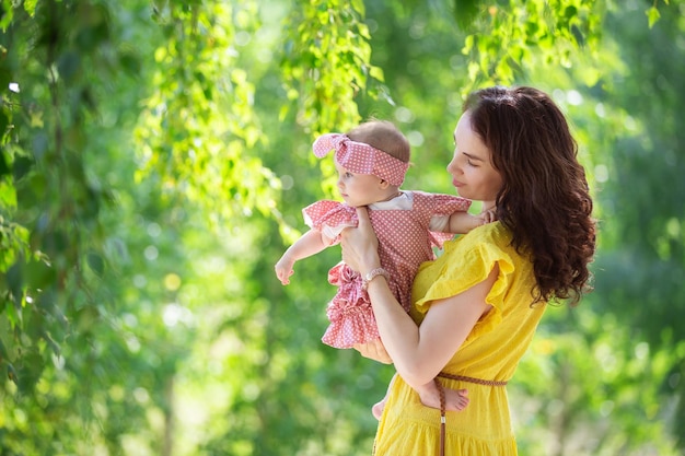 Uma mulher morena, uma jovem mãe com uma menina andando no parque