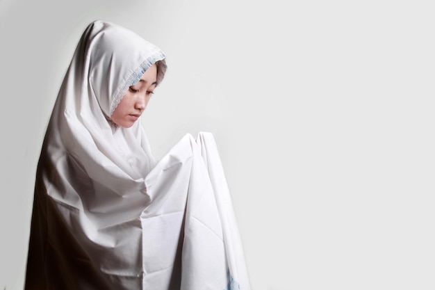 uma mulher muçulmana orando a Deus usando hijab branco