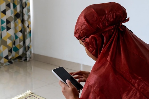 Uma mulher muçulmana segurando um smartphone e lendo o Alcorão digital em seu smartphone