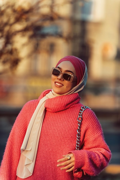 Uma mulher muçulmana vestindo um hijab anda pelas ruas da cidade em uma roupa moderna combinada com óculos de sol Foco seletivo