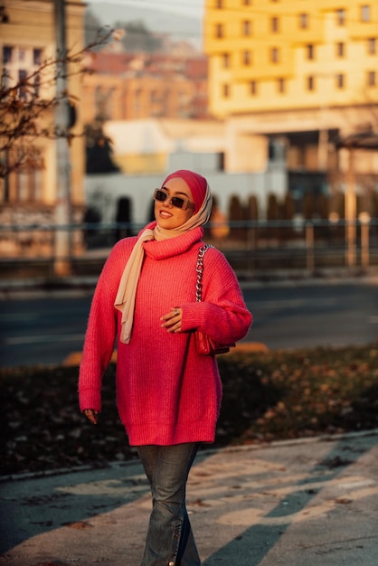Uma mulher muçulmana vestindo um hijab anda pelas ruas da cidade em uma roupa moderna combinada com óculos de sol Foco seletivo