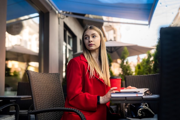 Uma mulher muito bonita com senso de estilo está sentada em um café em um laptop