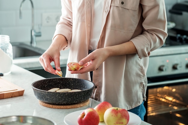 Uma mulher na cozinha coloca uma maçã fresca cortada em fatias em uma assadeira. cozinhando. cozimento de farinha de arroz