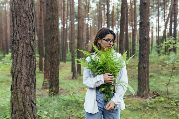 Uma mulher na floresta abraça um buquê de samambaias, uma jovem ativista protege a floresta