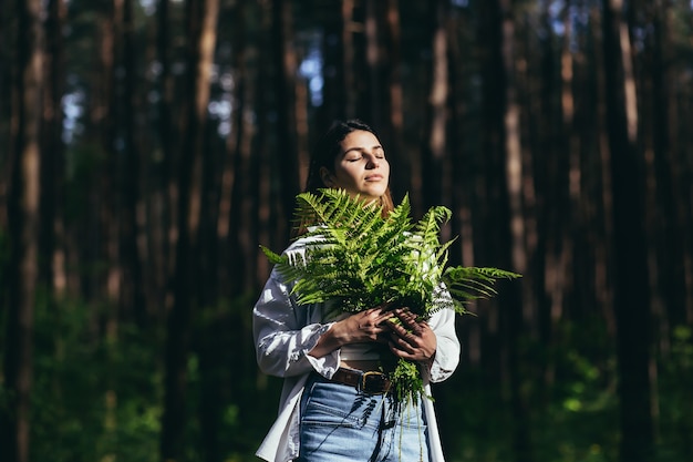 Foto uma mulher na floresta abraça um buquê de samambaias, uma jovem ativista protege a floresta