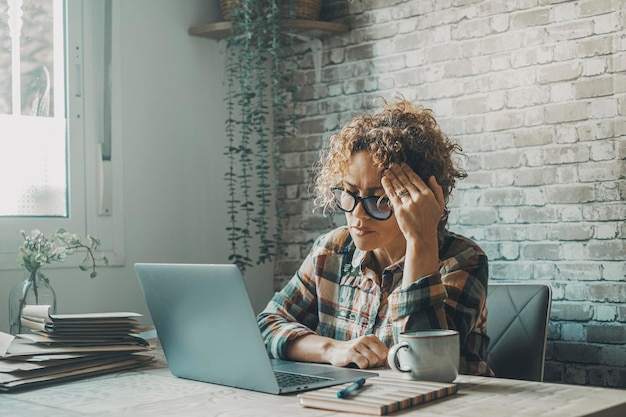 Uma mulher na mesa tocando a testa com expressão dolorosa no rosto Trabalhador on-line cansado e exausto com problemas de dor de cabeça e enxaqueca Estresse por excesso de trabalho mulheres modernas trabalho de negócios