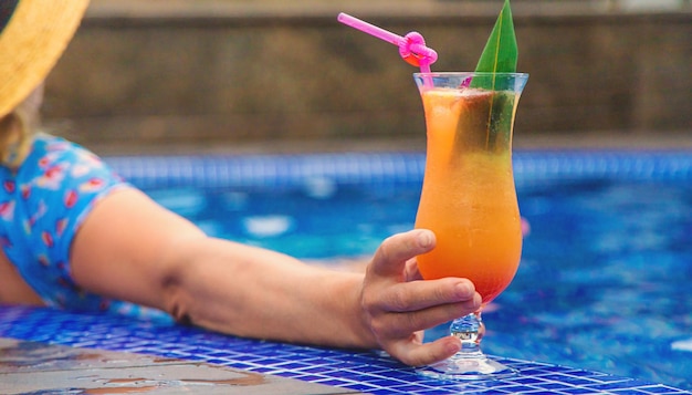 Uma mulher na piscina bebe um coquetel Foco seletivo