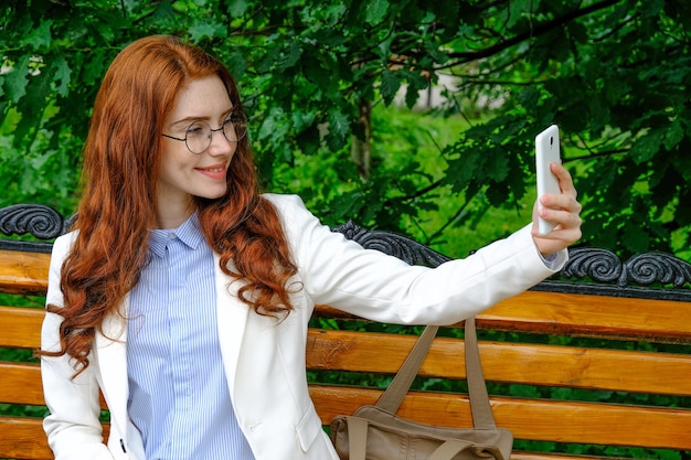 Foto uma mulher na rua tira uma selfie ao telefone