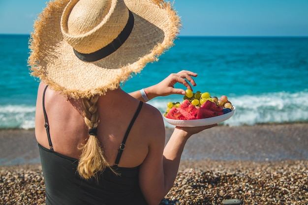 Uma mulher no mar come frutas. Foco seletivo.