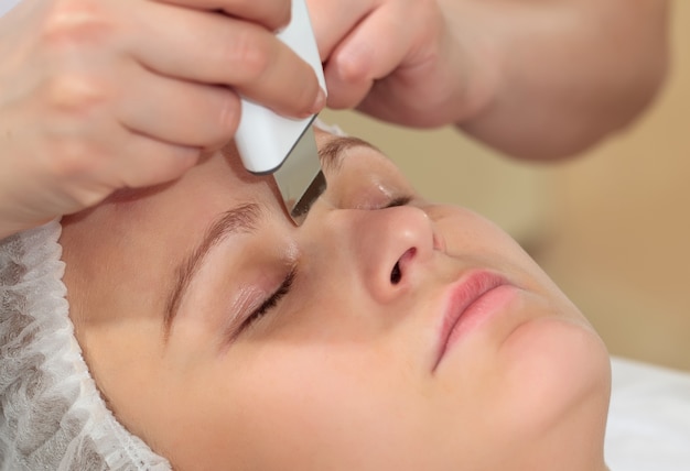 Uma mulher no spa de beleza recebendo tratamento facial com limpeza facial ultra-sônica