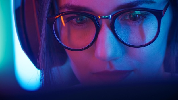 Uma mulher olha para a tela de um tablet iluminada com uma luz azul atrás dela.