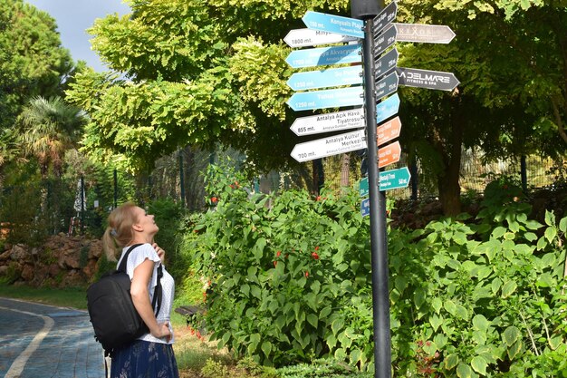 uma mulher olha para as placas de sinalização de madeira em uma floresta de verão procurando instruções