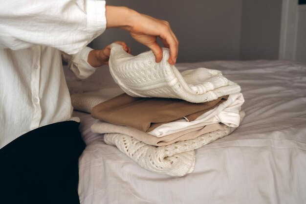 Uma mulher organizando tricô aconchegante e roupas neutras