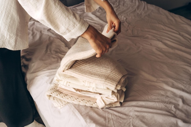 Uma mulher organizando tricô aconchegante e roupas neutras
