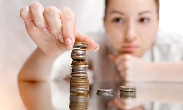 Uma mulher pensativa muda as moedas de uma pilha para outra. há uma torre de moedas. . foto de alta qualidade