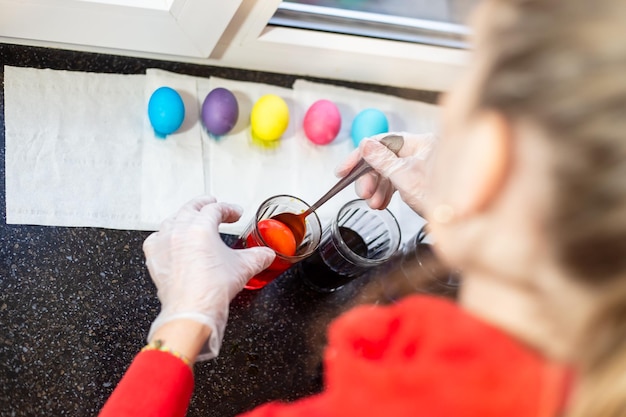 Uma mulher pinta ovos com tinta líquida e os coloca para secar em um guardanapo. Preparando-se para a festa da santa Páscoa