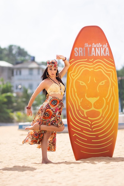 Uma mulher posa em frente a uma prancha de surfe com o logotipo do Sri Lanka.