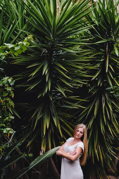 Uma mulher posa no contexto de palmeiras e natureza.