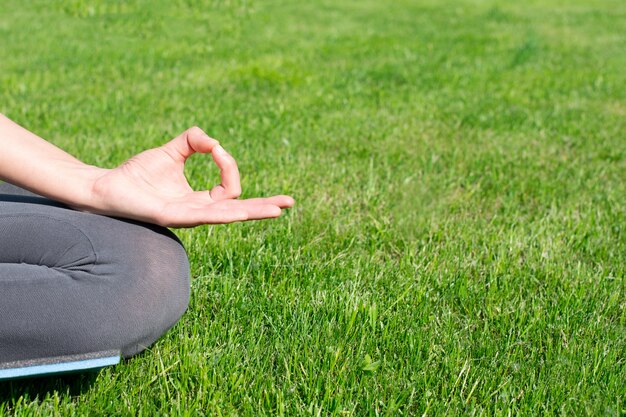 Uma mulher pratica ioga ao ar livre na grama. copie o espaço