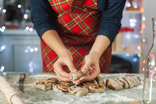Foto uma mulher prepara biscoitos de natal em casa na cozinha decorada para comida caseira de natal