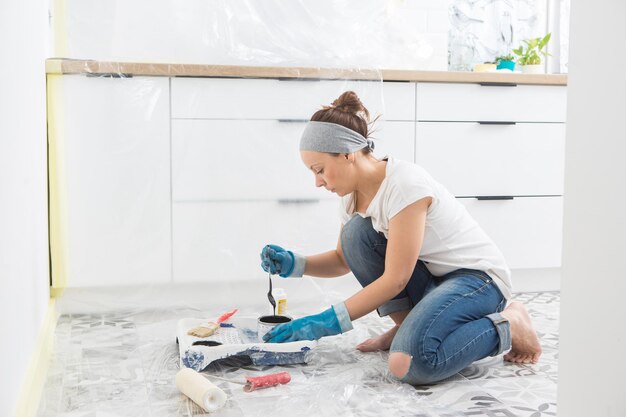 Uma mulher prepara tinta para pintar as paredes da cozinha Preparação de ferramentas e tintas para pintar