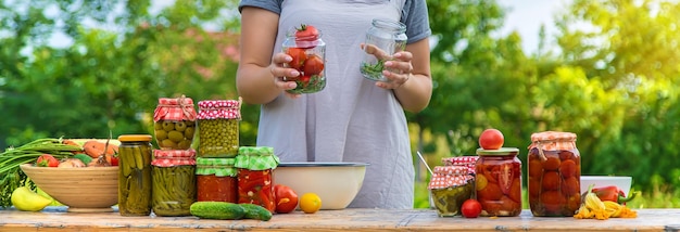 Uma mulher preserva legumes em potes Foco seletivo