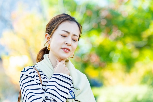 Uma mulher que se preocupa com dor de garganta ao ar livre