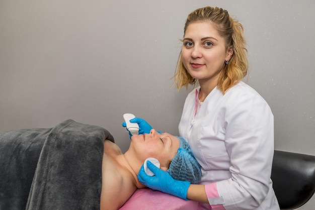 Uma mulher recebe peeling facial de cavitação ultra-sônica cosmetologia e cuidados com a pele limpeza facial