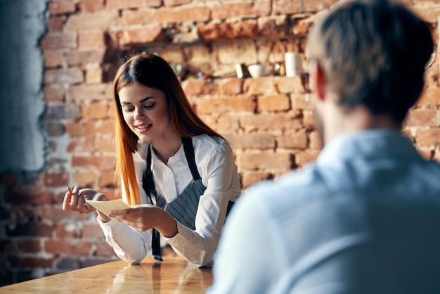 Uma mulher recebe um pedido de um homem em um café que serve um garçom