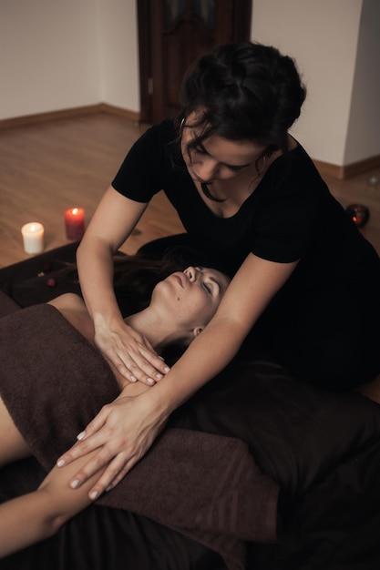 Uma mulher recebendo uma massagem com uma vela ao fundo