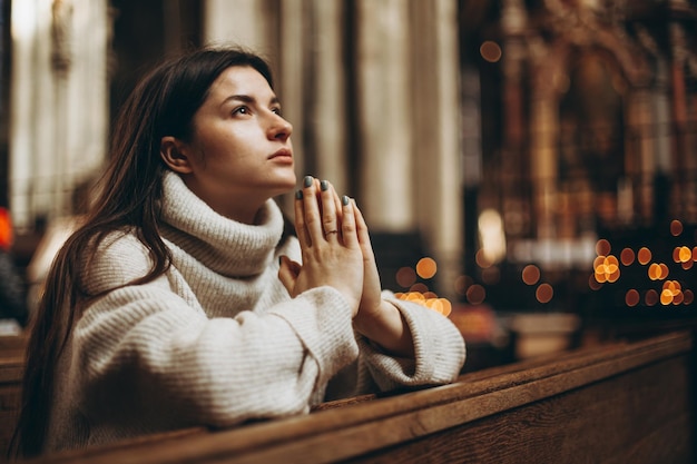 Uma mulher rezando de joelhos em um antigo templo católico a Deus copie o espaço